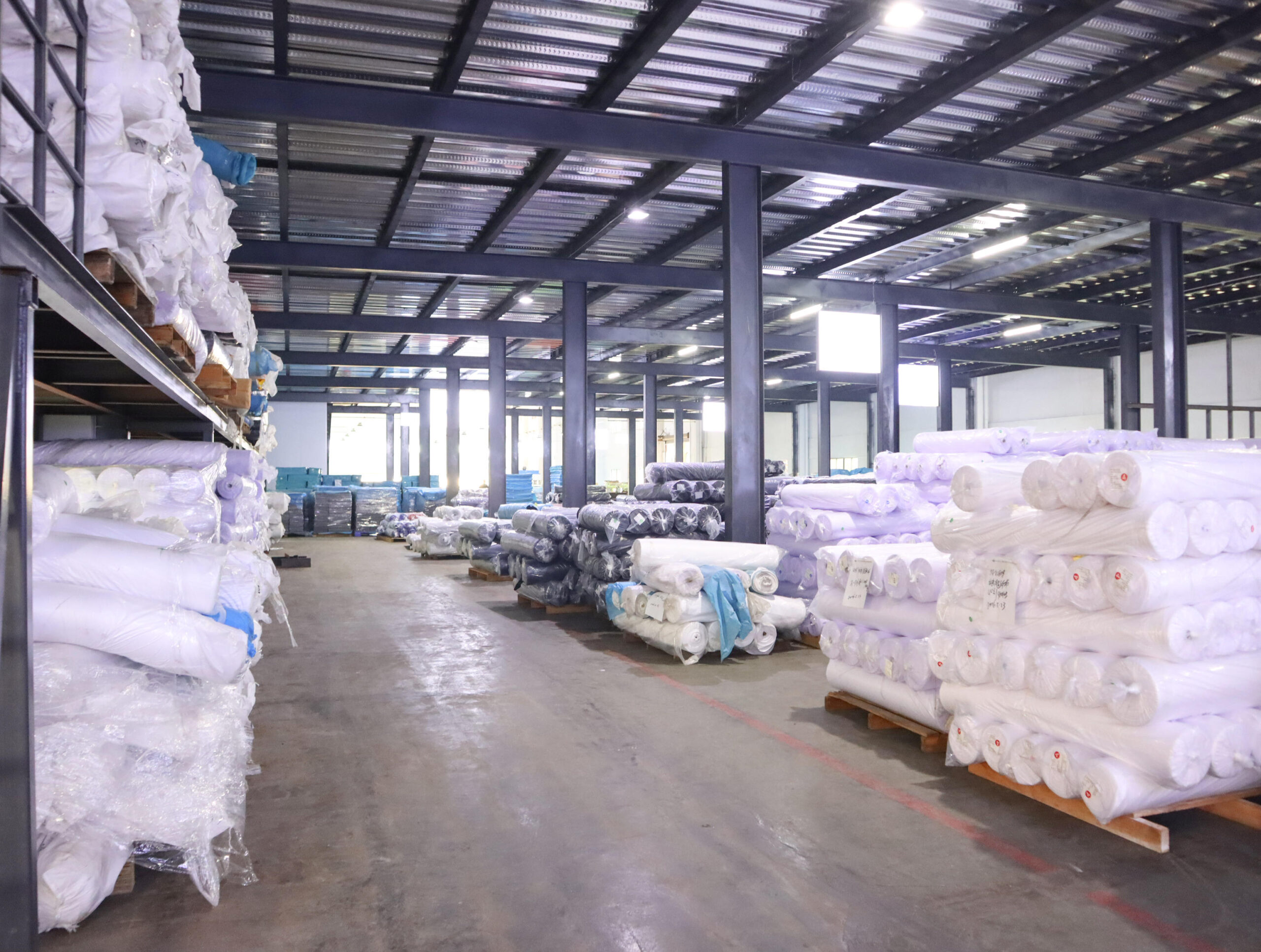 AICO Yoga factory warehouse storing rolls of production material for OEM and ODM manufacturing.